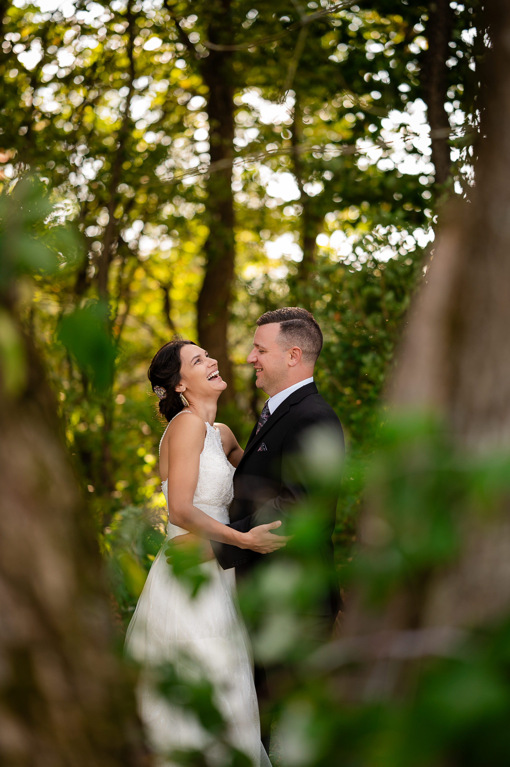 Newlyweds laughing together in a sunlit woodland portrait